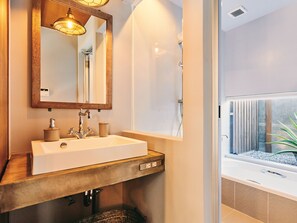 A modern bathroom with a large sink, mirror, and a view of a spa area. - IMAGINE OKINAWA (Nakijin)