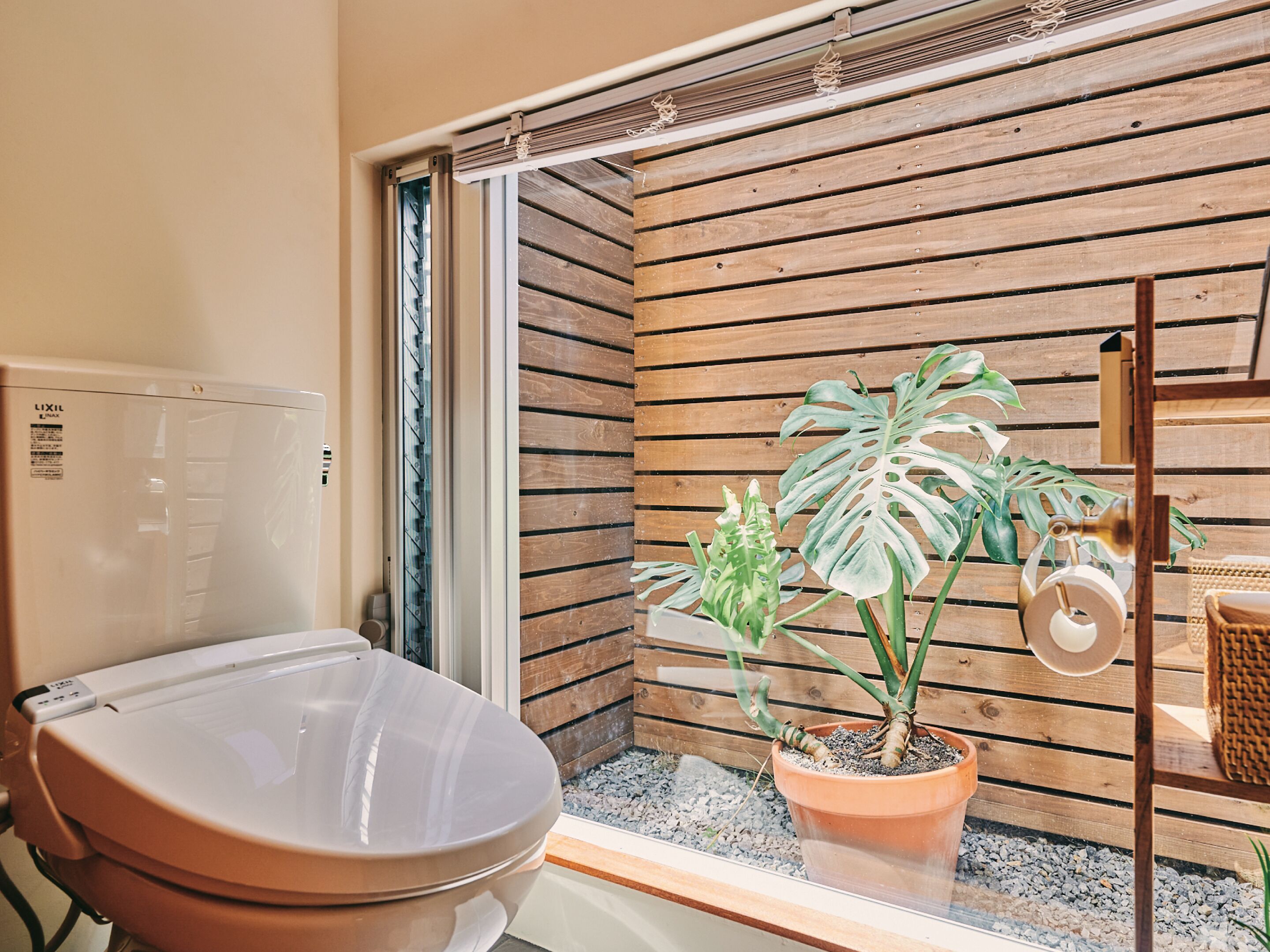 A bathroom with a toilet, a wooden wall, and a potted plant.