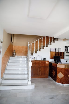 A staircase leading to a reception area with a desk, computer, and framed certificates. - Hotel Cruce Chauchina (Chauchina)