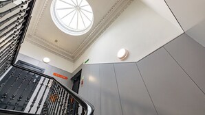 Un interior modern amb una escala, un fanal i un senyal que indica el pis.