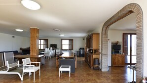 Uma sala ampla com mesa de jantar, cadeiras, cozinha e uma janela grande.