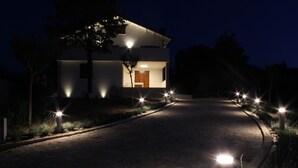 Uma casa moderna com entrada pavimentada e iluminação externa.