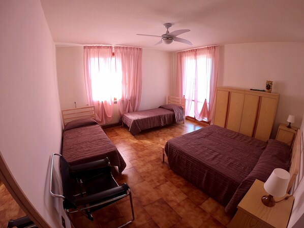 Un dormitorio con dos camas individuales, un escritorio, una silla, un armario y un ventilador de techo.
