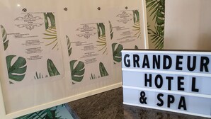 A framed spa menu with services like foot soak, massage, and bath. A sign reads "GRANDEUR HOTEL & SPA". - Grandeur Hotel and Spa (Malacca City)
