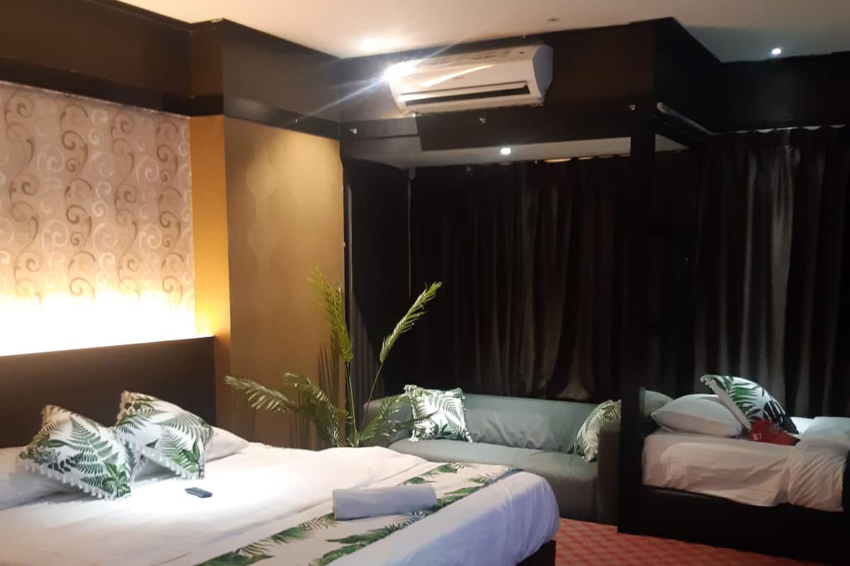 Habitación de hotel con una cama grande, una cama más pequeña, un televisor de pantalla plana, un escritorio y una ventana con cortinas.