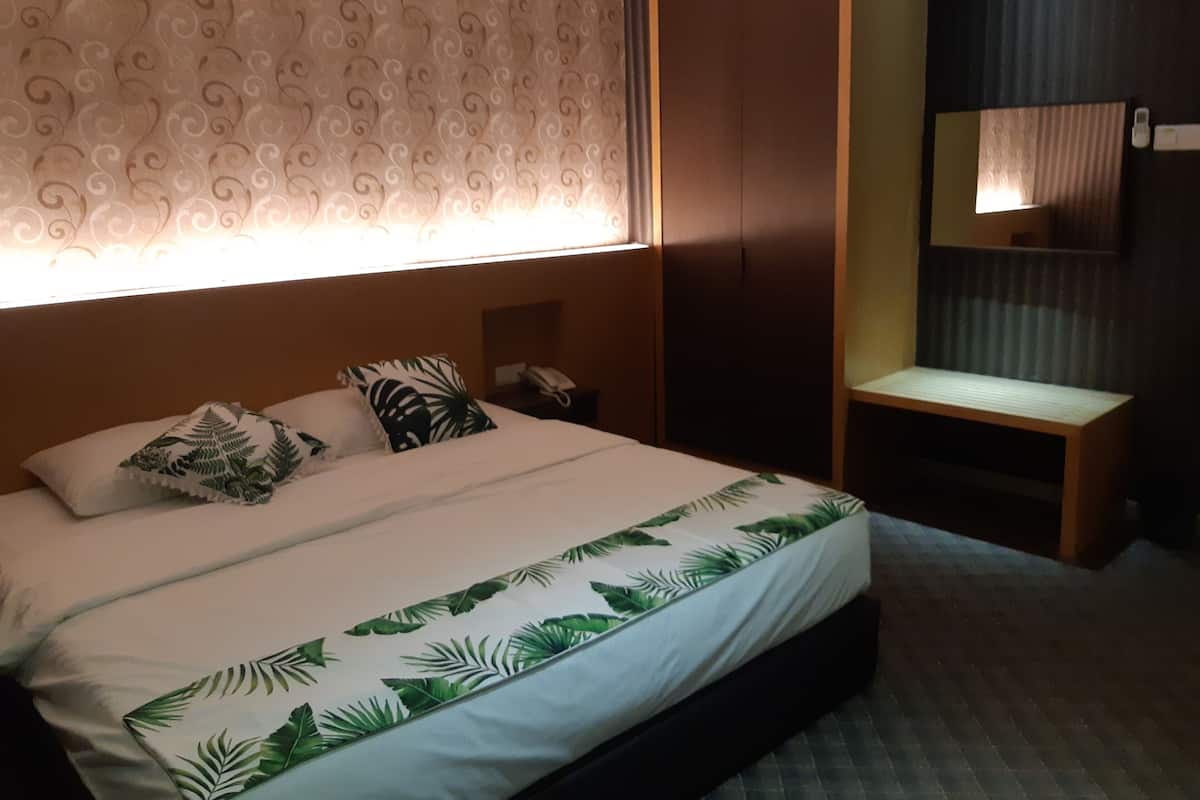 Una habitación de hotel con cama, mesita de noche, espejo y armario.