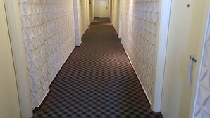 A hallway with patterned walls and carpet, leading to a door at the end. - Grandeur Hotel and Spa (Malacca City)