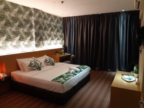 Une chambre d’hôtel avec un lit, un petit bureau, un téléphone et une fenêtre avec des rideaux.