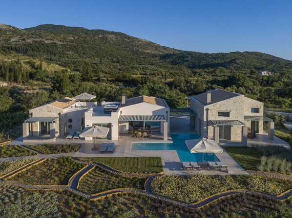 A modern villa with a swimming pool, outdoor seating, and a landscaped garden.