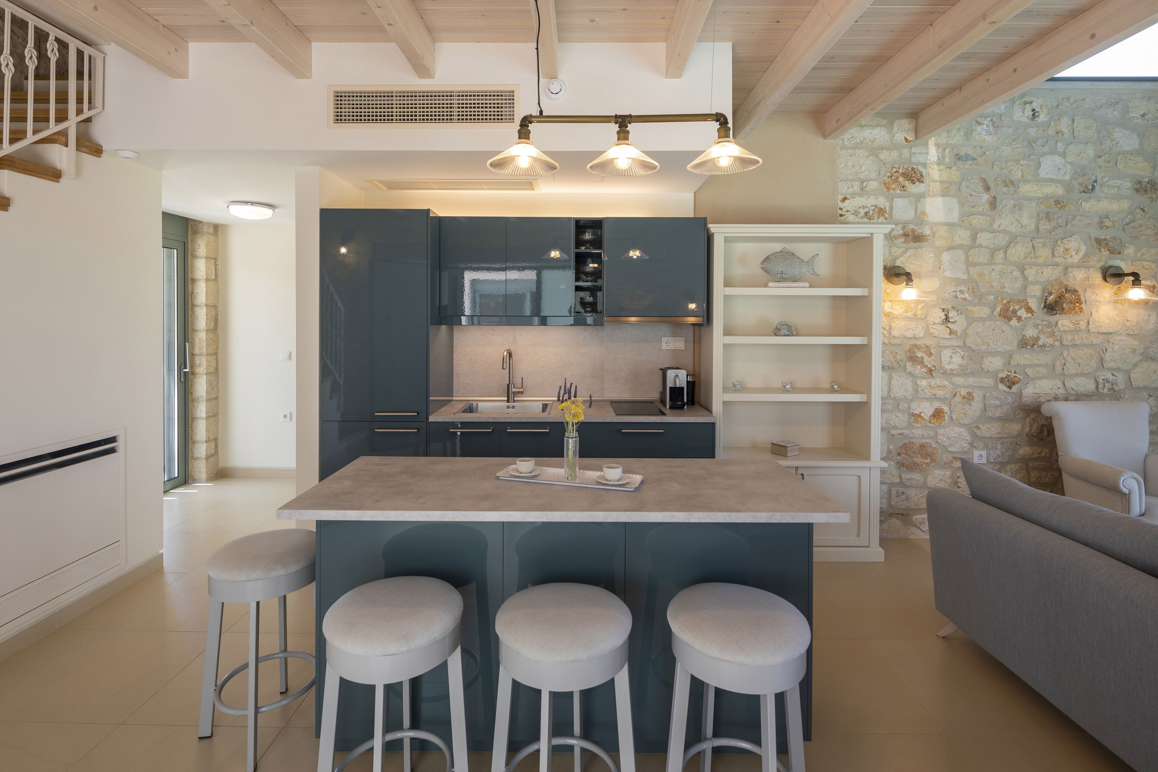 Una cocina moderna con una isla central, taburetes de bar y una pared de acento de piedra.
