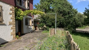 A stone pathway leading to a house with a wooden fence and a garden with various flowers. - Welcome to our vacation home Martini! (Waldachtal)