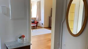 A room with a wooden floor, a marble-top dresser, a mirror, and a door leading to another room. - Welcome to our vacation home Martini! (Waldachtal)