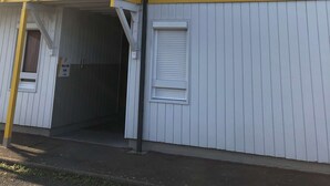 A multi-story building with a yellow balcony railing, a garage door, and a small window. - Premiere Classe Rennes Ouest - Le Rheu (Le Rheu)