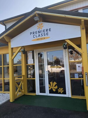 A hotel entrance with a yellow facade, glass doors, and a sign reading "Premiere Classe Hotels". - Premiere Classe Rennes Ouest - Le Rheu (Le Rheu)