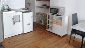 Une cuisine compacte avec des meubles blancs, un four à micro-ondes et un coin repas comprenant une table et des chaises.