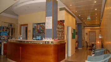 Zona de recepción con un mostrador curvo, un cartel que dice "ARNO" y un panel de menú adherido a la pared.