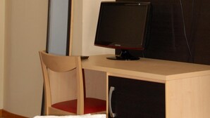 A hotel room with a desk, chair, and a large mirror.