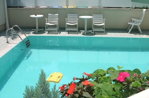Una piscina al aire libre de temporada, sombrillas, tumbonas