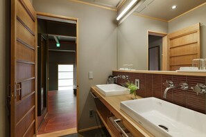 A modern bathroom with two sinks, wooden flooring, and a large mirror. - Tasokare Machiya House (Kyoto)