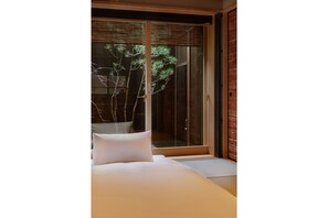 A bedroom with a large sliding glass door leading to a bamboo garden. - Tasokare Machiya House (Kyoto)