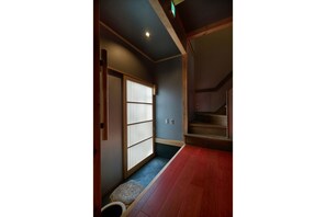 A traditional Japanese interior with tatami flooring, a sliding door with shoji screens, and a wooden staircase. - Tasokare Machiya House (Kyoto)
