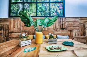 A wooden dining table with a yellow vase, wooden crates, and green plates.