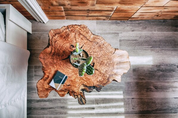 A round wooden table with a notebook and two small potted plants.
