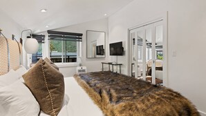 A modern bedroom with a large bed, a flat-screen TV, and a view of the outdoors. - Remodeled Aspen Gem! 1 Block to Aspen Mtn, Balcony with Views, W/D, Parking & Walk to Town (Aspen)