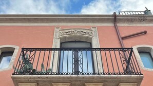 En bygnings facade med en balkon, udsmykket med detaljerede stensnitter og et smedejernsgelænder.