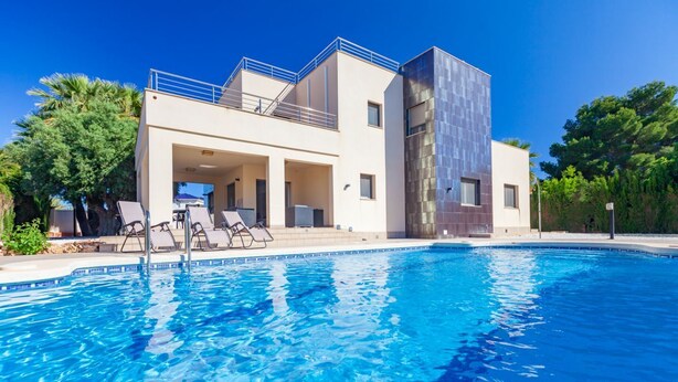 Un hôtel moderne doté d’une piscine, de chaises longues et d’un espace extérieur couvert.
