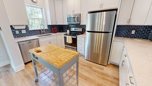 A modern kitchen with stainless steel appliances, a wooden countertop, and a tiled backsplash.