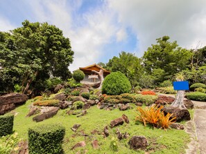 Une maison entourée d’une végétation luxuriante, sous un ciel dégagé.