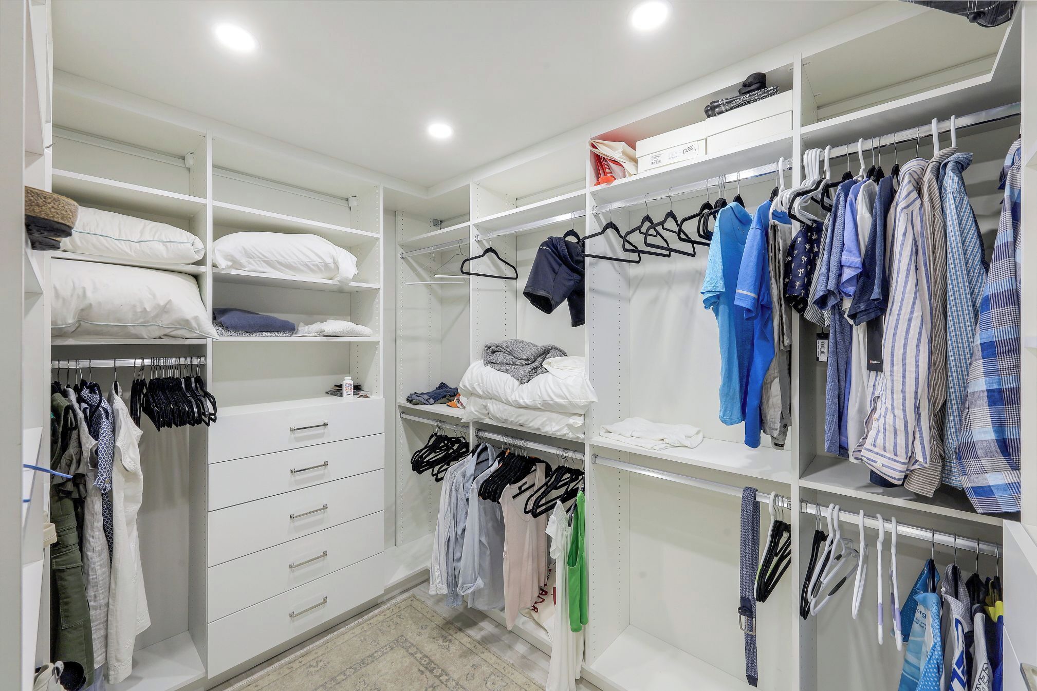 Un vestidor amplio con estantes, cajones y espacio para colgar ropa.