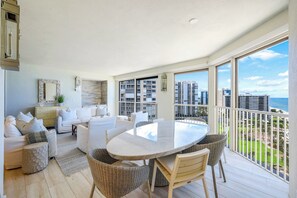 A spacious balcony with a dining table and chairs, overlooking a cityscape and the ocean. - La Mer at Park Shore (Naples)