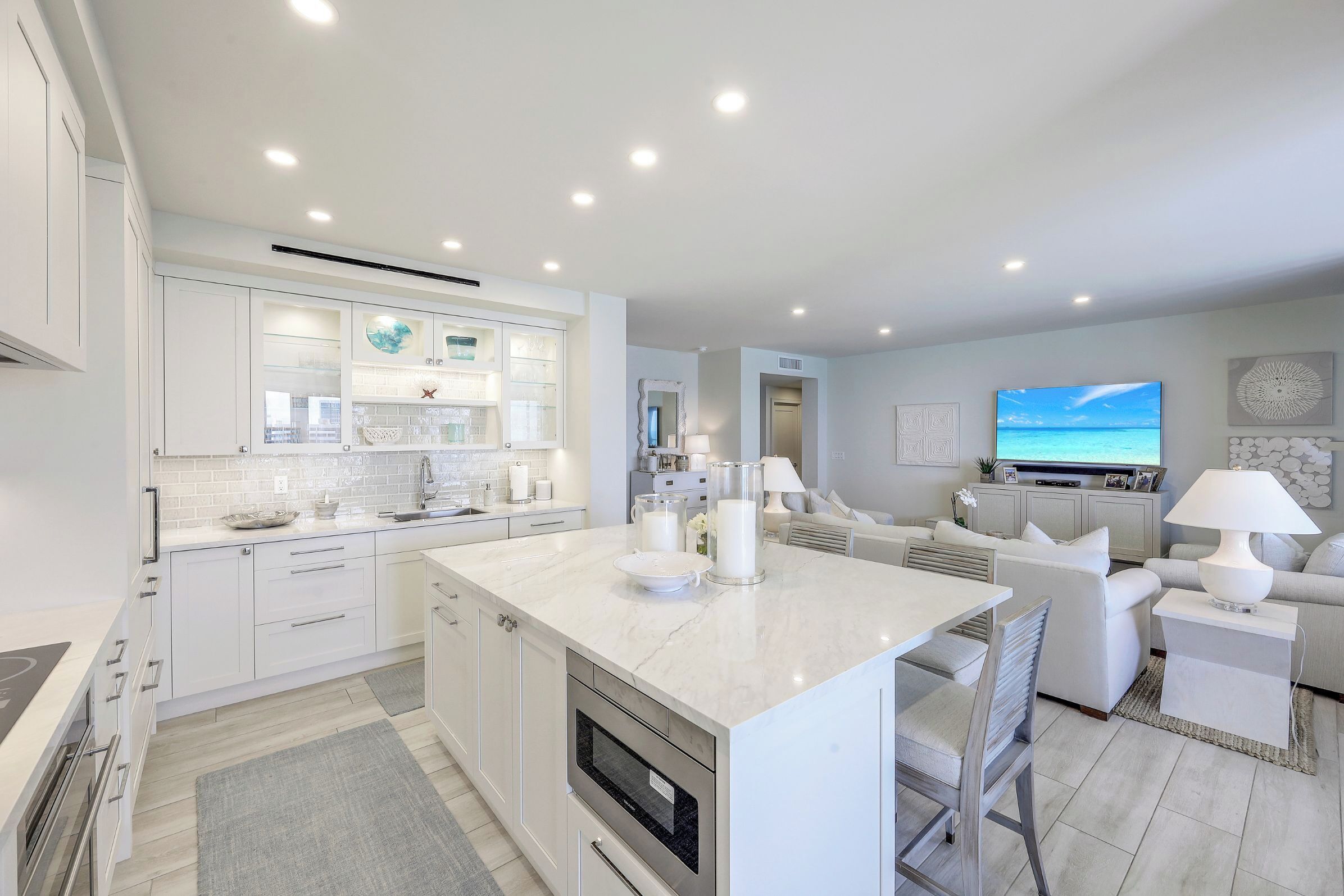 A modern kitchen with white cabinetry, a central island, and a built-in oven.