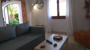 Una sala de estar con un sofá, una mesa de centro con un reloj y una ventana con cortinas.