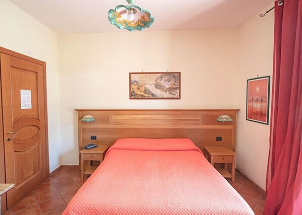 A bedroom with a wooden bed, two bedside tables, a nightstand, a decorative ceiling light, and a framed picture on the wall. - Hotel Sottovento (Sant'Egidio del Monte Albino)