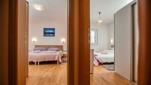 Un dormitorio con dos camas, suelo de madera, un cuadro en la pared y una ventana con persianas.