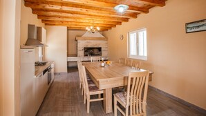 Una cocina con techo de madera, horno de piedra y una mesa de comedor con sillas.
