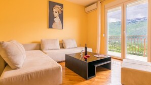 Uma sala de estar com um sofá bege, uma mesa de centro preta e um quadro na parede.