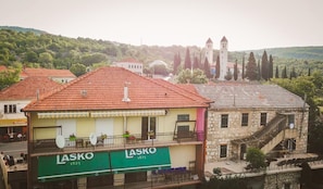 A building with a green sign labeled "LASKO 1825" and a balcony with outdoor seating.