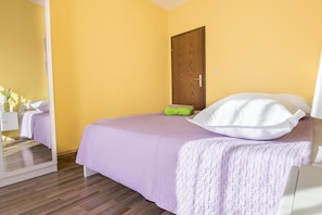 A bedroom with a bed, a wooden door, and a mirror.