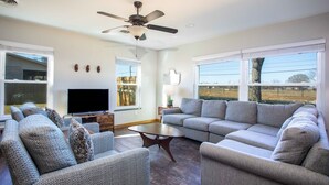 A living room with a sectional sofa, a television, and a ceiling fan. - The Green Pony | Pet-friendly (Fredericksburg)