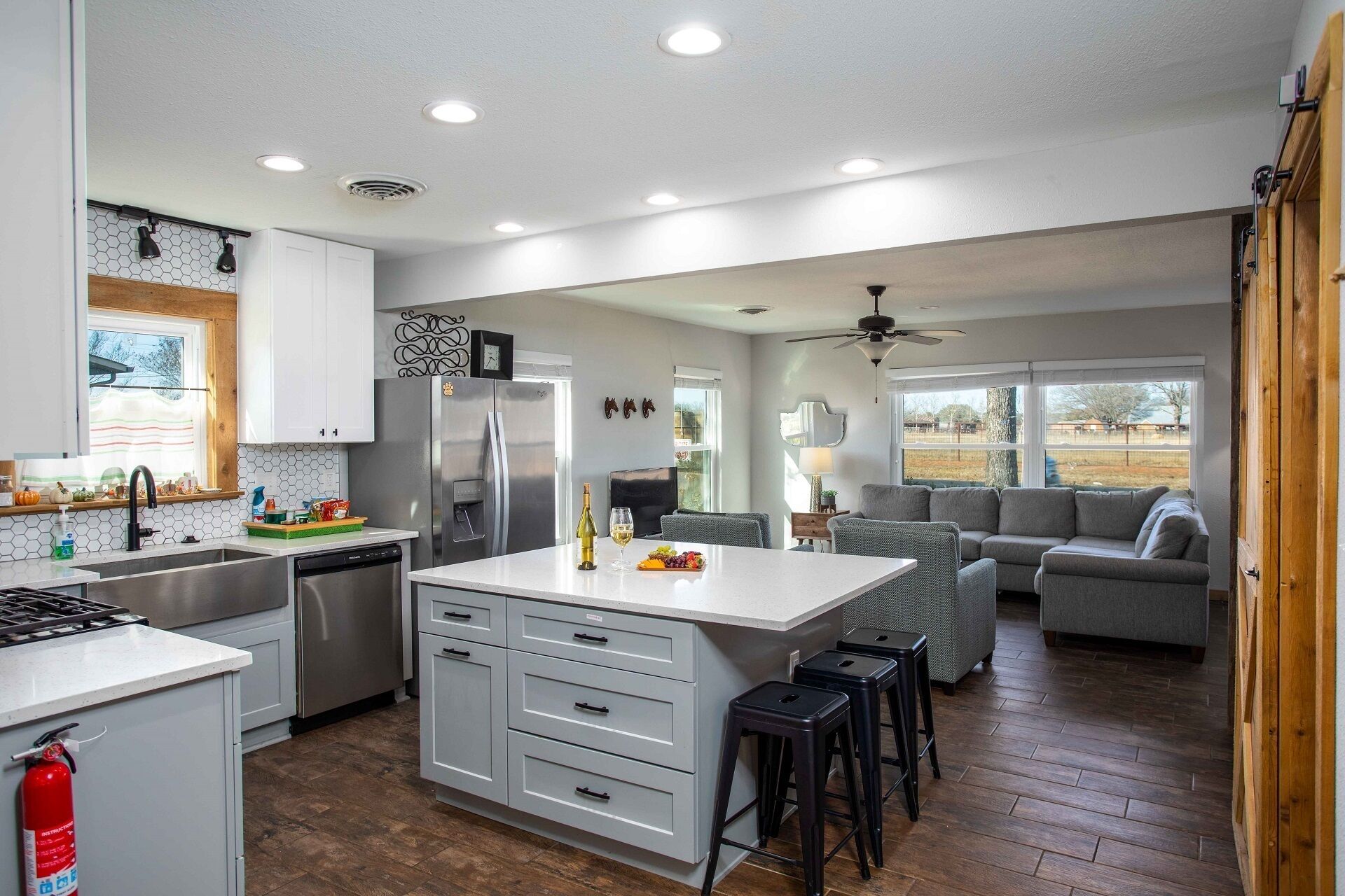 A modern kitchen with a central island, a dining area with a sofa, and a view of the outdoors.