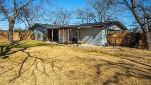 A single-story house with a covered patio, a fenced yard, and a wooden deck. - The Green Pony | Pet-friendly (Fredericksburg)