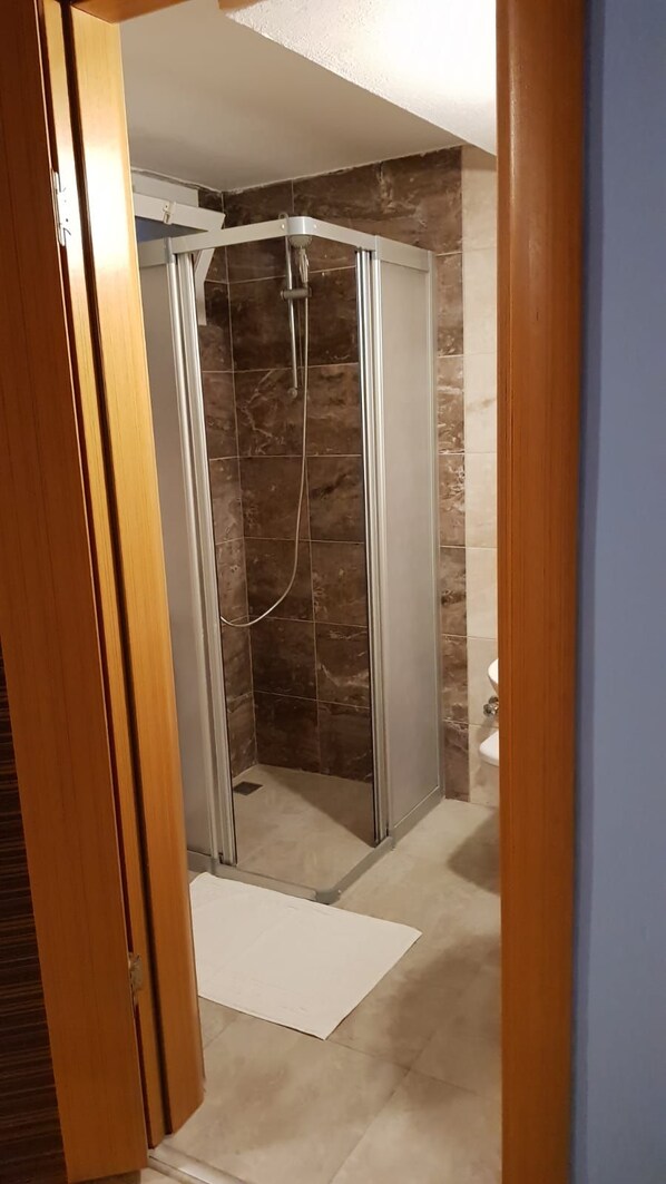 A bathroom with a glass shower enclosure, a toilet, and a shower curtain.