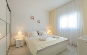 A neatly arranged bedroom with a large bed, two bedside tables, a lamp, and a window with curtains. - Holiday Home Lucija (Kastela)