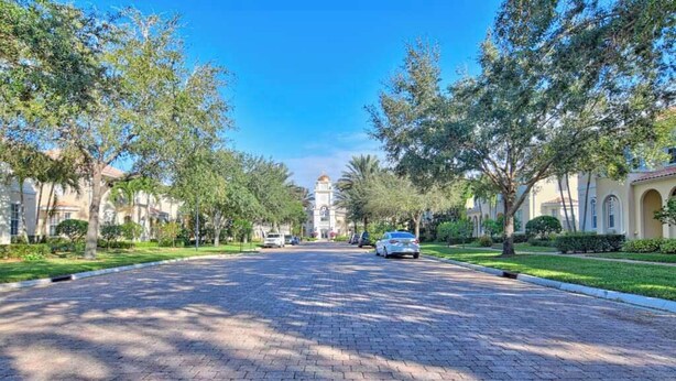 Una strada pavimentata fiancheggiata da alberi e edifici, che conduce a un edificio centrale con una cupola.