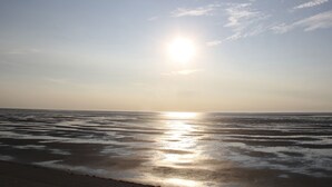 A beach with the sun reflecting on the water. - Vacation apartment, ground floor, WLAN, covered terrace, wood-burning stove (Krummhörn)