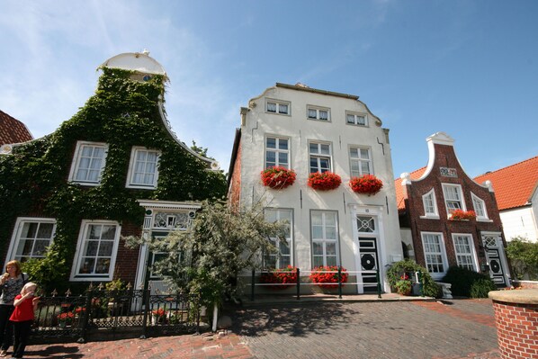 A historic building with a white facade, red brick accents, and a distinctive curved roof.